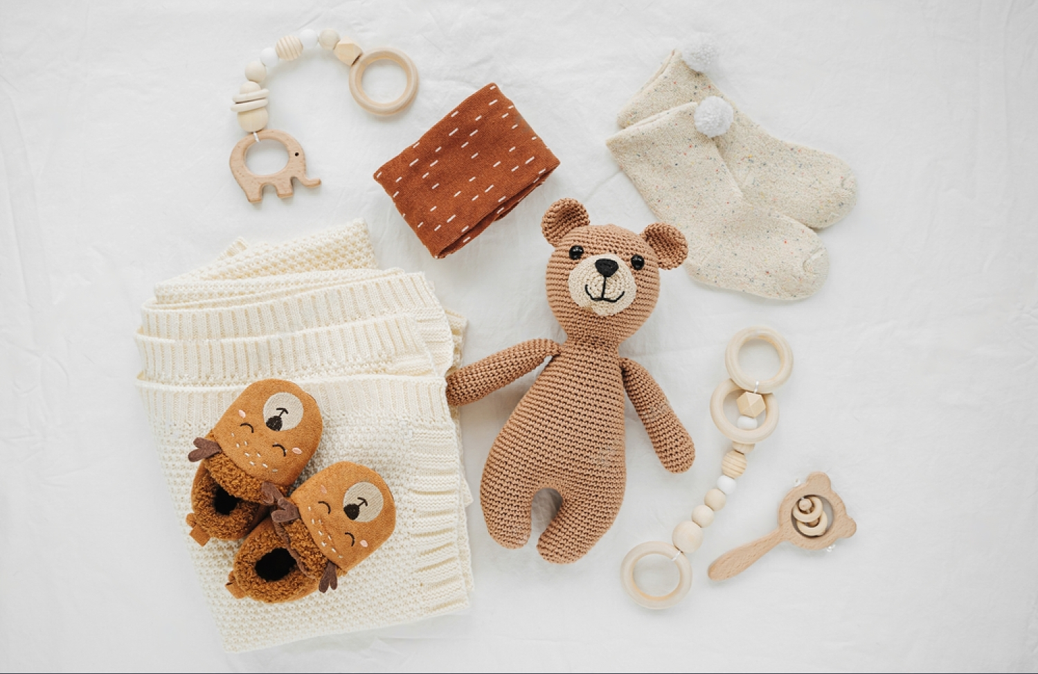 stock-photo-knitted-toy-bear-blanket-socks-and-wooden-teether-for-newborn-on-white-bed-gender-neutral-1660398916-i9EyEkj4A-transformed